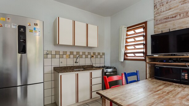 Cocina compacta con refrigerador, estufa, microondas y un comedor con sillas.
