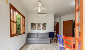 A room with a grey sofa, a ceiling fan, and three framed leaf artworks on the wall. - Comfortable Apt 270m From the Beach Stcy101 (Florianópolis)