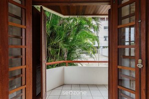 A corner balcony with wooden doors and a view of a building in the background. - Charming Apt 270m From the Beach Stcy102 (Florianópolis)