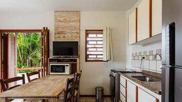 A compact kitchen with a dining area, a television, and a window with curtains.