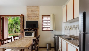 A compact kitchen with a dining area, a television, and a window with curtains. - Charming Apt 270m From the Beach Stcy102 (Florianópolis)