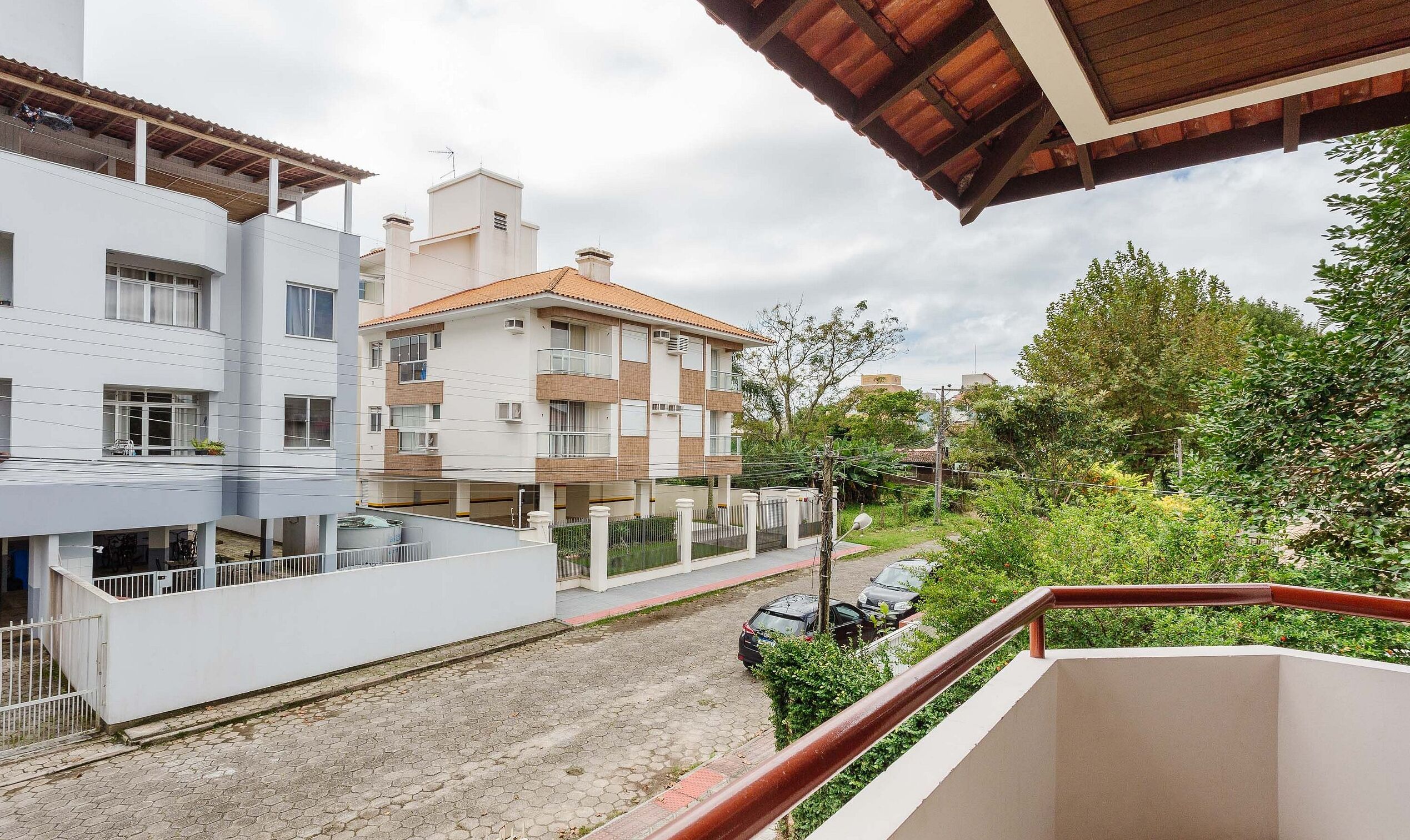 A residential building with multiple balconies, a paved driveway, and surrounding greenery.