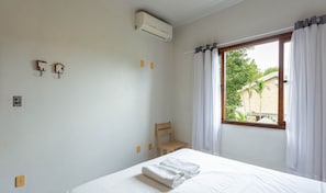 A bedroom with a bed, a chair, an air conditioning unit, and a window with curtains. - Nice Apartment 270m From the Beach Stcy201 (Florianópolis)