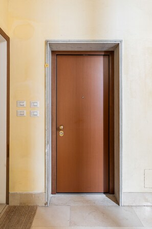 A closed wooden door with a brass handle and a keyhole, a small brass doorknob, and a number '8' sign on the wall to the left. - San Gervasio Apartment by Wonderful Italy (Bologna)