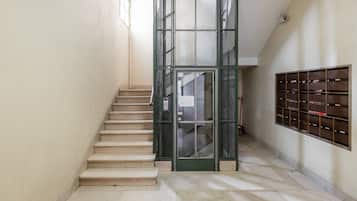 Een trap met een metalen poort die leidt naar een kamer met een wandgemonteerde archiefkast.
