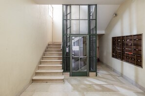 A staircase with a metal gate leading to a room with a wall-mounted filing cabinet. - San Gervasio Apartment by Wonderful Italy (Bologna)