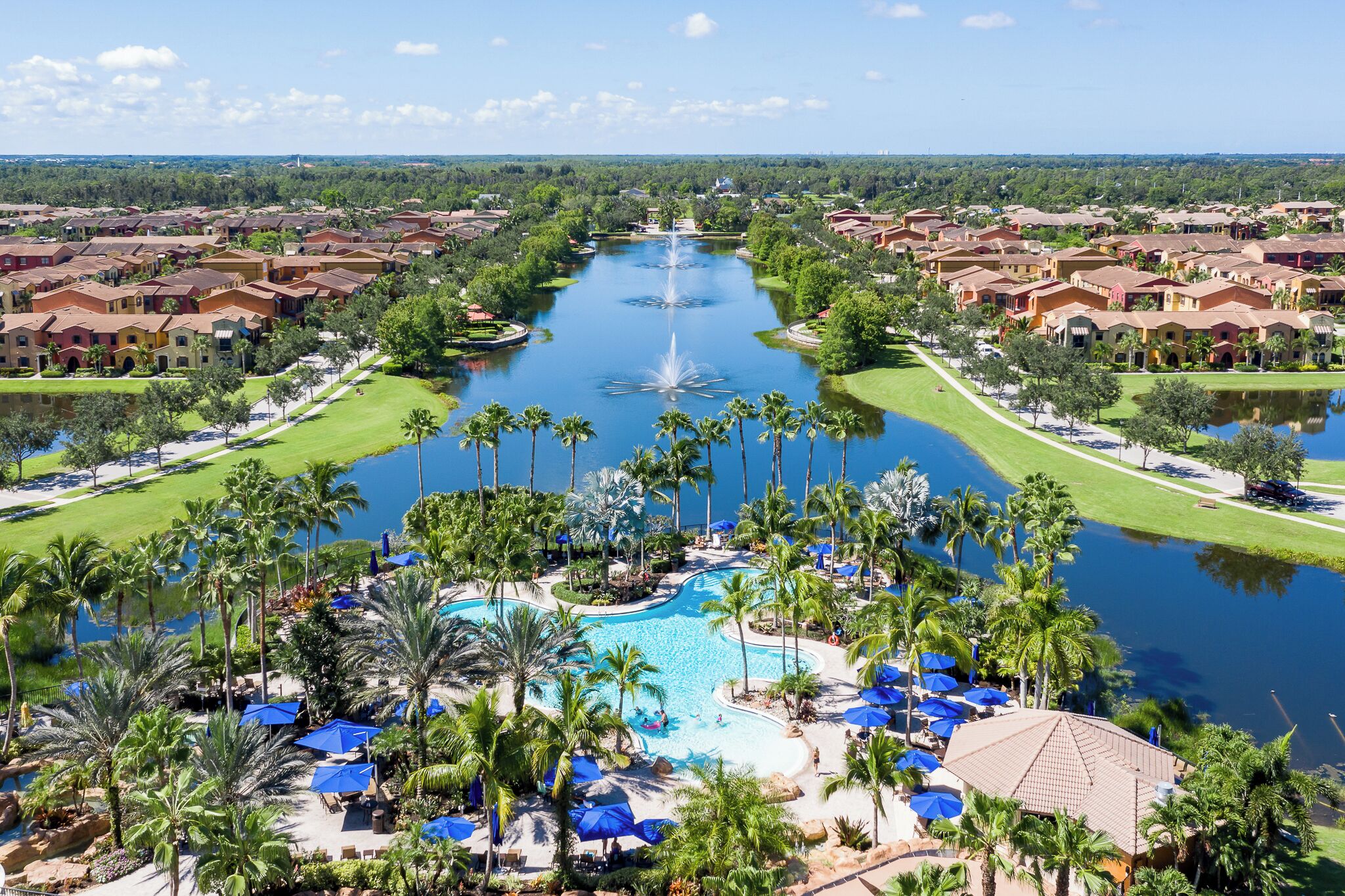 A resort with a central water feature, a swimming pool, and surrounding greenery.