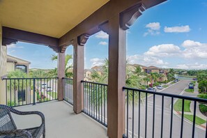 A balcony with a view of a residential street, palm trees, and a clear sky. - 3bed/2.5Resort-style Paseo QUAD home w/semi-private pool. (Fort Myers)