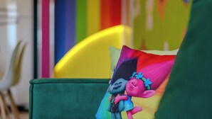 A green chair with a colorful pillow featuring a cartoon character. - 2-bedrthemed Rainbow Ap With Barbecue Obp0301 (Penha)