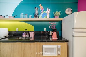 Cozinha com micro-ondas, cafeteira e vários utensílios sobre o balcão.