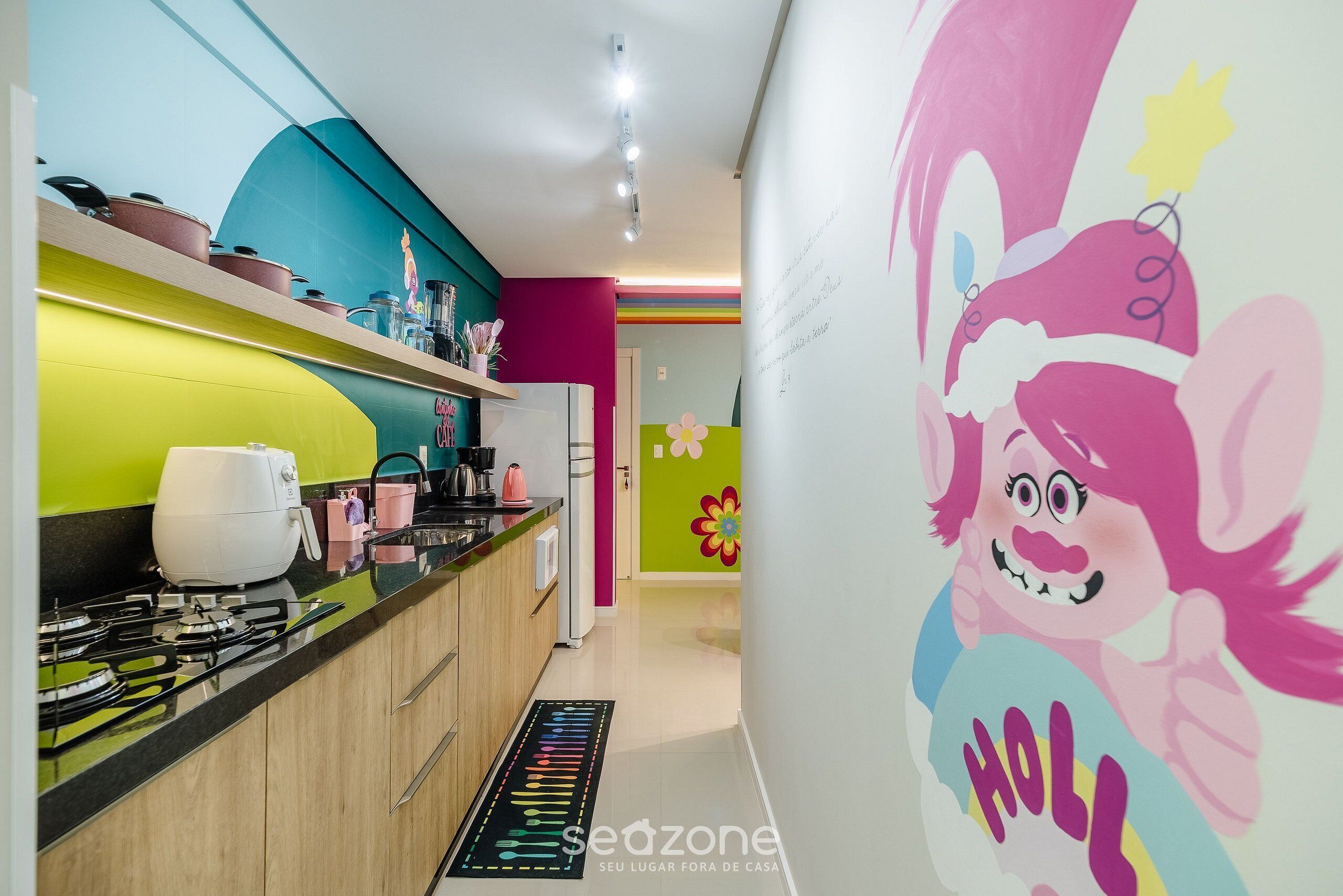 Une cuisine équipée d’appareils électroménagers modernes, agrémentée d’un crédence colorée et d’une fresque murale festive.