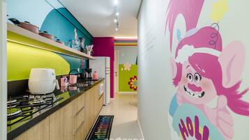 Une cuisine équipée d’appareils électroménagers modernes, agrémentée d’un crédence colorée et d’une fresque murale festive.