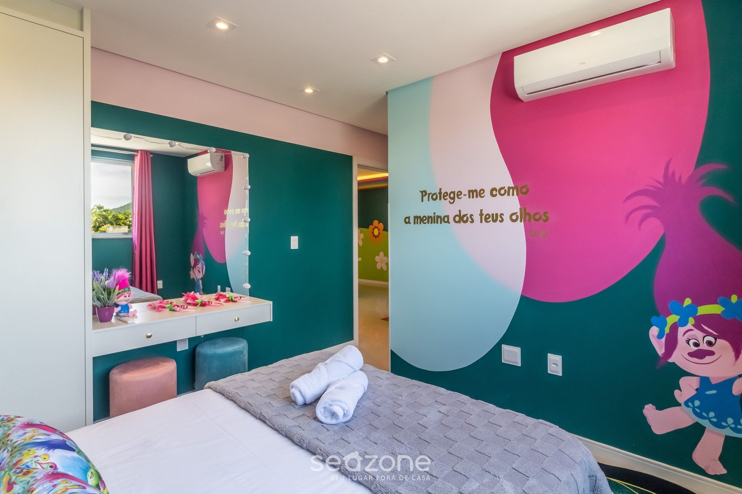Une chambre à coucher avec un lit, une coiffeuse avec un miroir et un mur décoré d’un personnage de dessin animé.