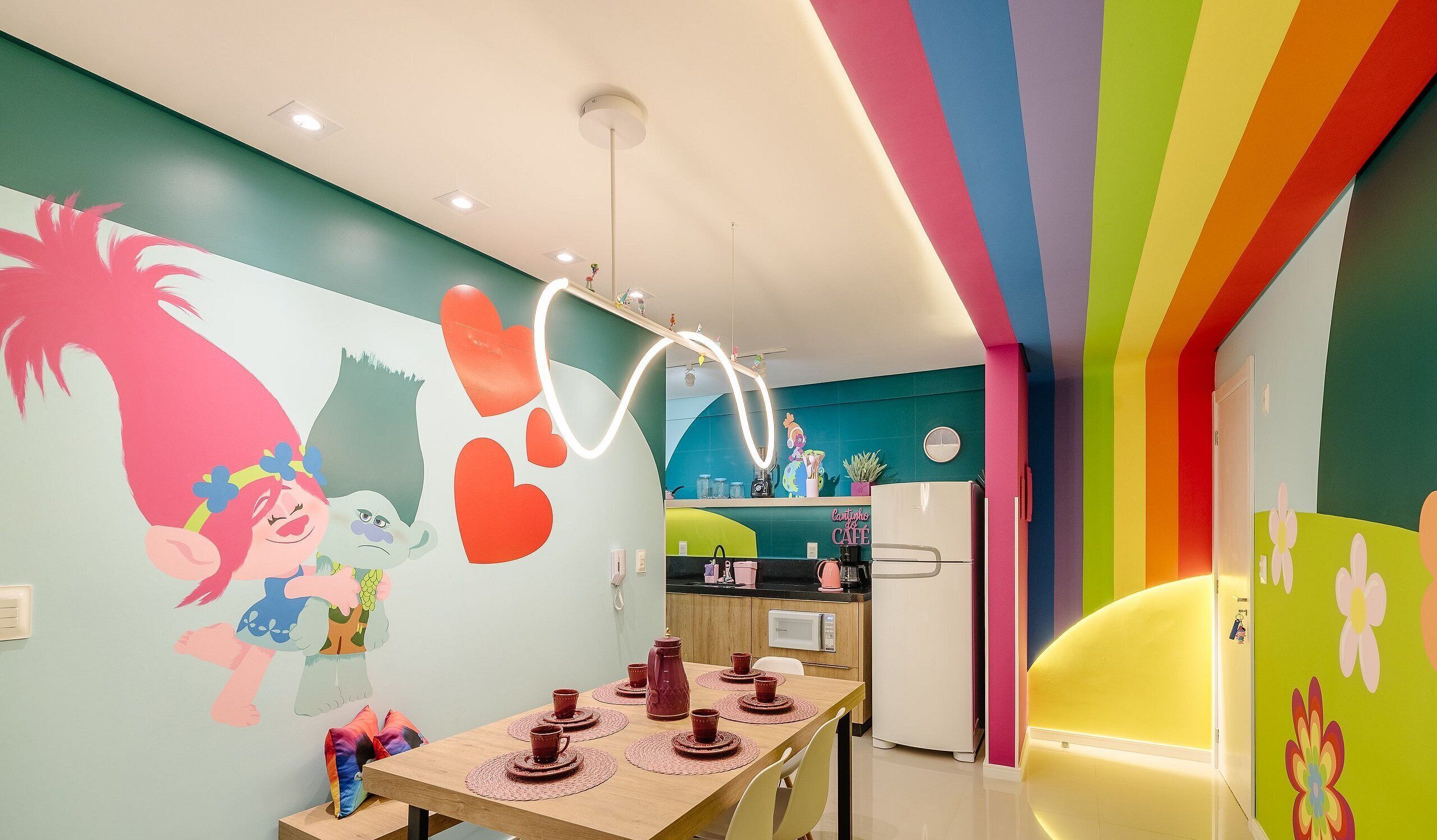 Une cuisine aux couleurs vives, dotée d’un coin repas, d’une fresque murale, d’un réfrigérateur et d’un four à micro-ondes.