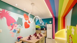 A brightly colored kitchen with a dining area, featuring a wall mural, a refrigerator, and a microwave. - 2-bedrthemed Rainbow Ap With Barbecue Obp0301 (Penha)