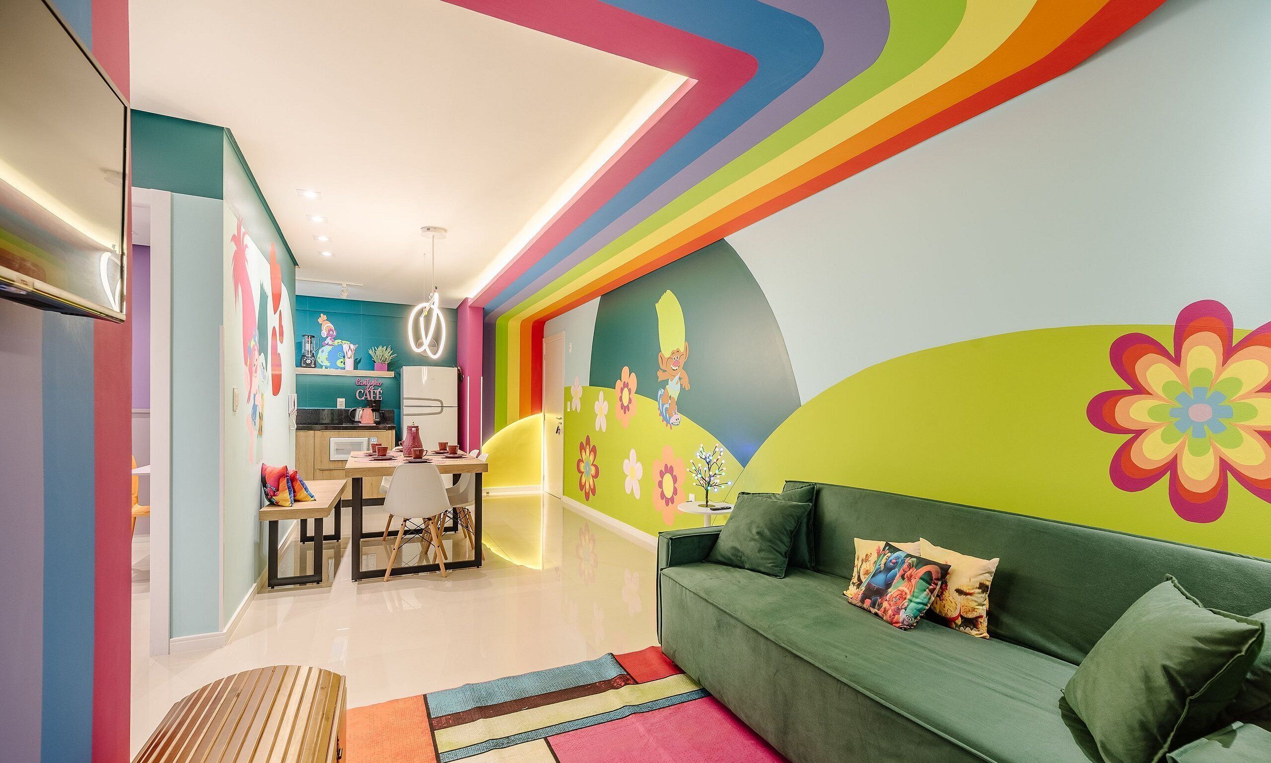 Une chambre d’enfant pleine de vie, avec un canapé, des œuvres d’art colorées sur les murs et un coin cuisine.