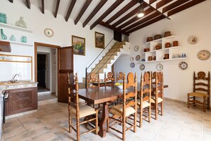 A dining area with a wooden table and chairs, a staircase, and shelves with decorative plates. - Son Idò by Rentallorca (Muro)