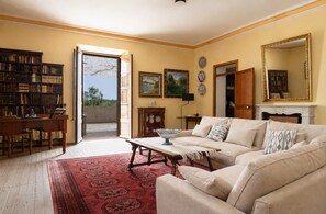 A living room with a sofa, a coffee table, a bookshelf, and a door leading to a balcony. - Son Idò by Rentallorca (Muro)