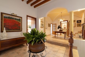 A well-lit hallway with a large painting, a potted plant, and a wooden bench. - Son Idò by Rentallorca Mallorcan essence amidst the gardens (Muro)