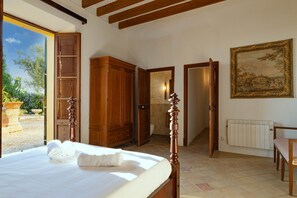 A bedroom with a bed, wooden wardrobe, and a painting on the wall. - Son Idò by Rentallorca (Muro)