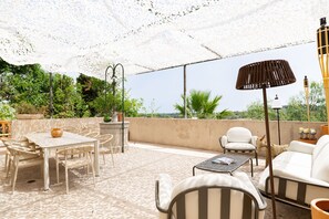 Eine Terrasse im Freien mit Tisch, Stühlen, einer Lampe und Blick auf Grünflächen.