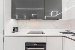 A modern kitchen with white cabinetry, a stainless steel range hood, and a built-in oven. - Luxury City Apartment in Birmingham (Birmingham)