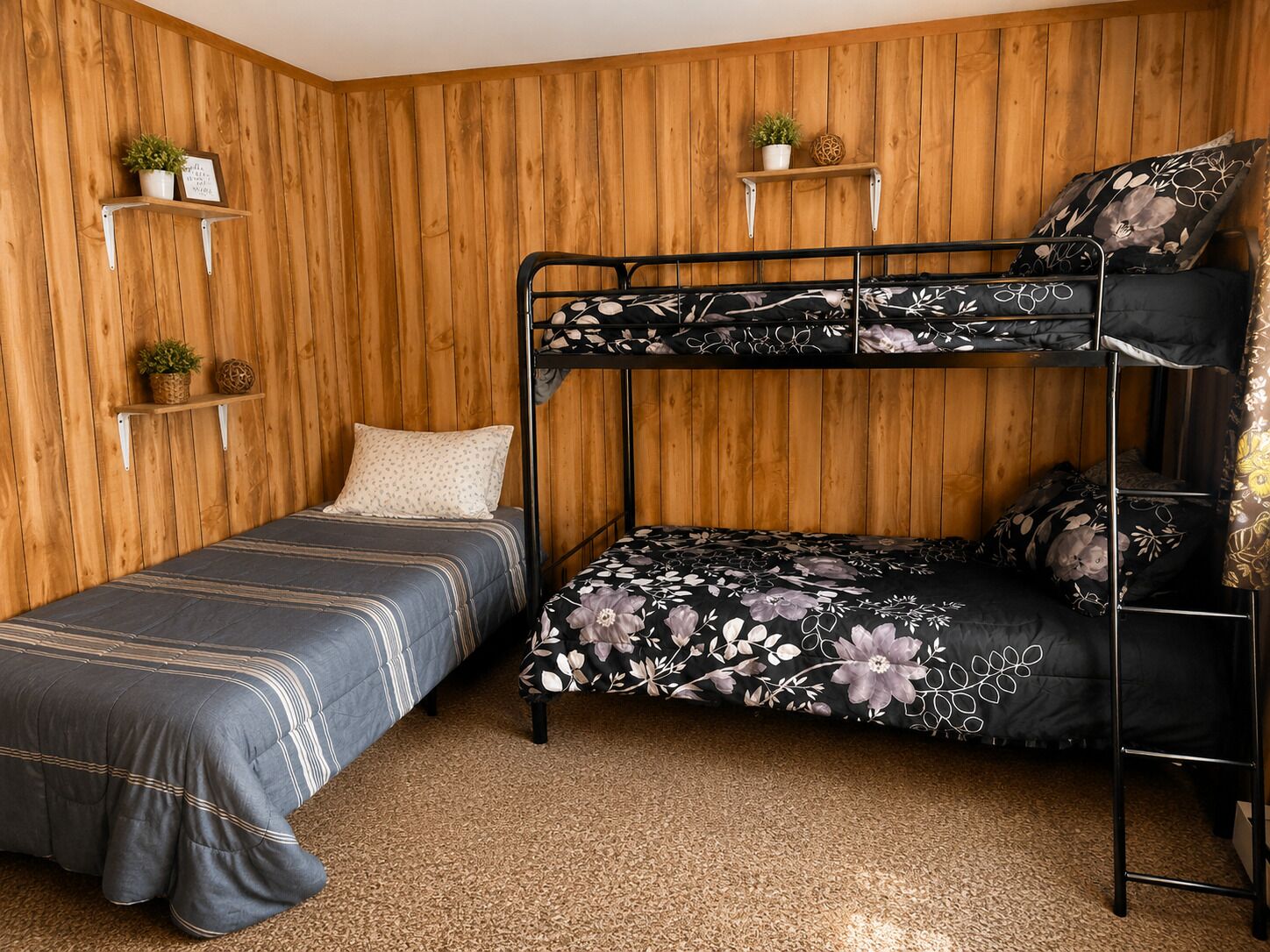A bunk bed room with two beds, wooden panel walls, and shelves with plants.