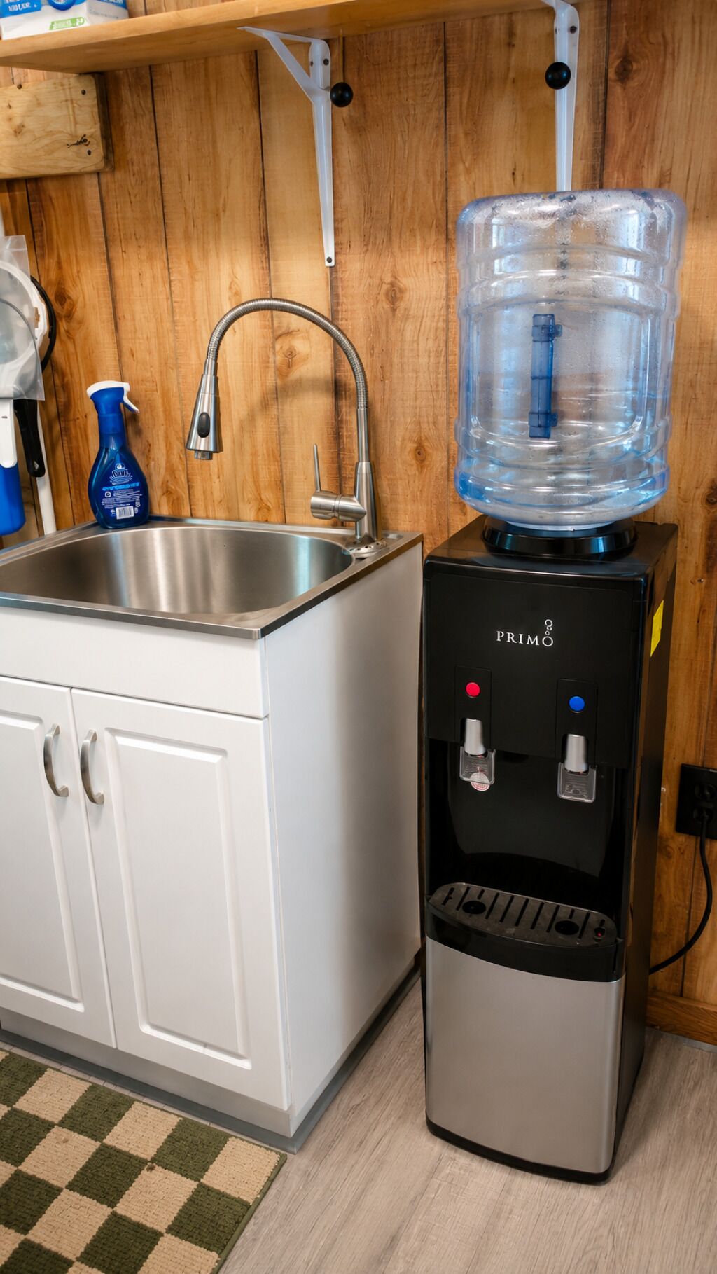 A kitchen with a stainless steel sink, a water dispenser, and a large water jug.
