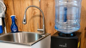 A kitchen with a stainless steel sink, a water dispenser, and a large water jug.
