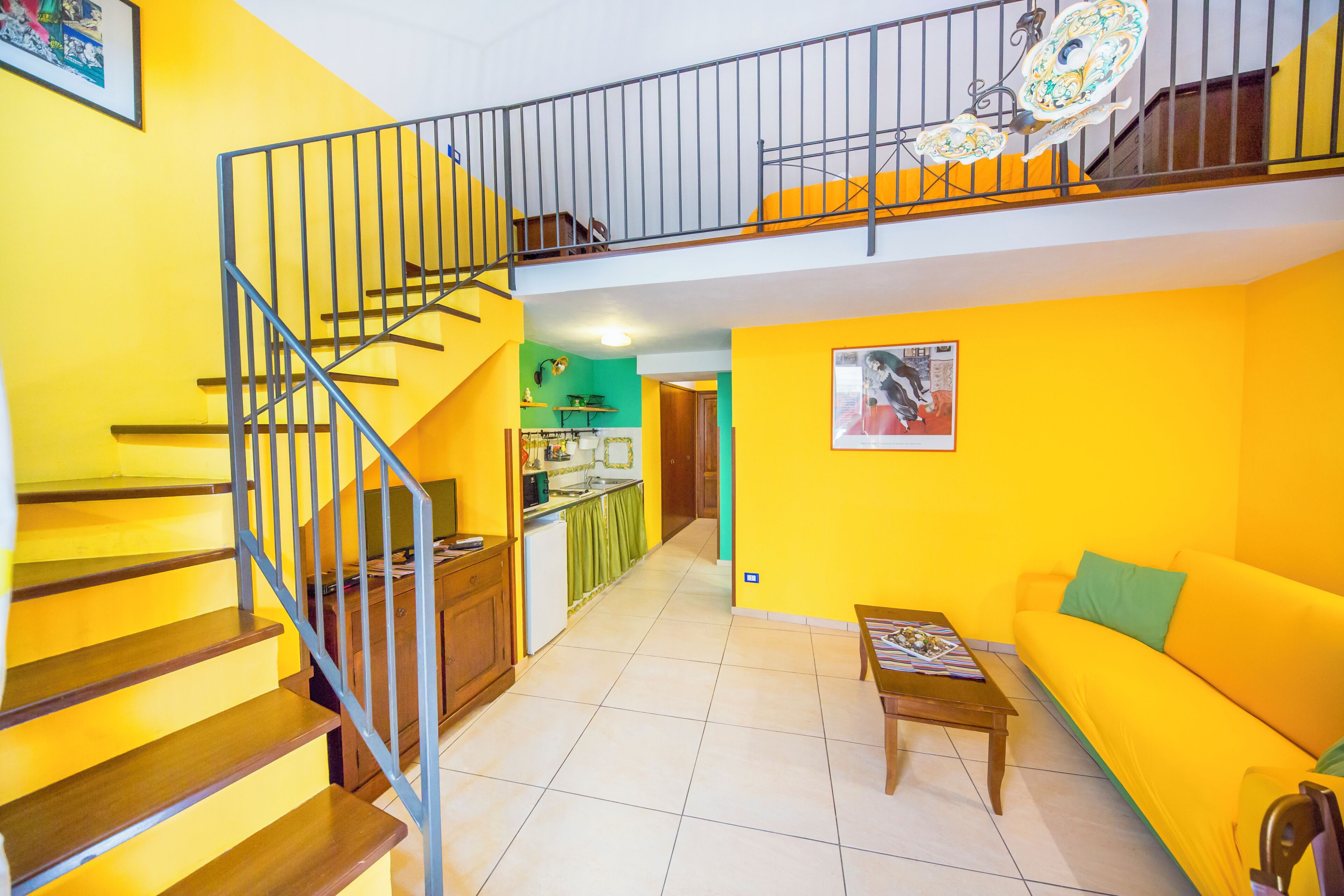 Eine mehrstöckige Wohnung mit Treppe, Küche, Wohnbereich und einer Couch.