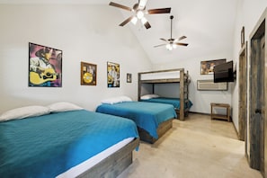 A room with bunk beds, a ceiling fan, and wall-mounted artwork.