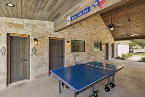 Una mesa de ping pong en un espacio cubierto con paredes de piedra y puertas con los letreros 'Outhouse' y 'Joplin Express'.