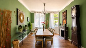 Una sala da pranzo con tavolo e sedie in legno, un lampadario, un camino e un orologio a pendolo.