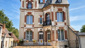 Un edificio a due piani con un balcone, ampie finestre e facciata in mattoni.
