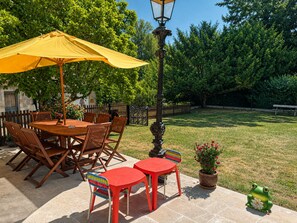 An outdoor patio with a wooden table and chairs, a yellow umbrella, and a lamp post. - Clemenceau Residence | 4 bedrooms, 4 bathrooms, garden, downtown (Cosne-Cours-sur-Loire)