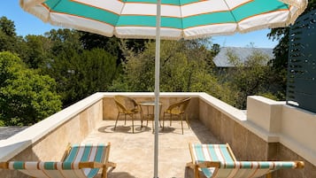 A patio with two striped lounge chairs, a table, and a striped umbrella.