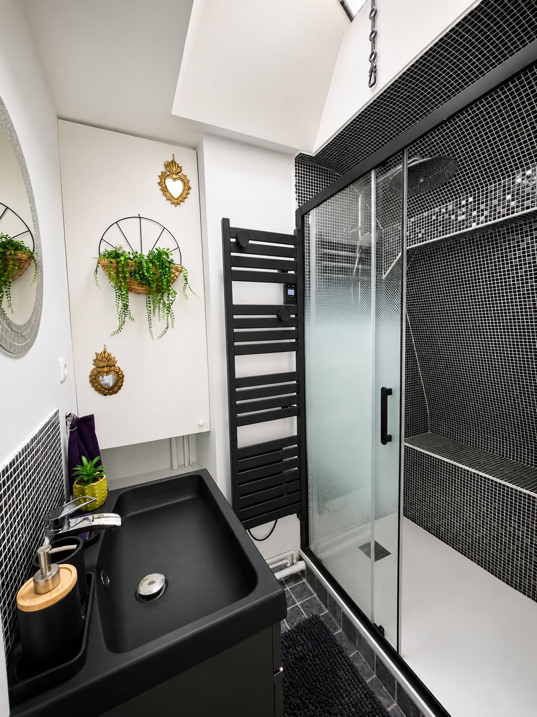 Une salle de bain moderne avec un lavabo noir, une douche en verre et des jardinières décoratives fixées au mur.
