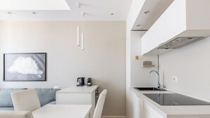 A modern kitchen with a built-in stove, a sink, and a dining area with a table and chairs. - San Gervasio Apartment by Wonderful Italy (Bologna)