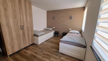 A bedroom with two beds, a wardrobe, and a built-in bench.