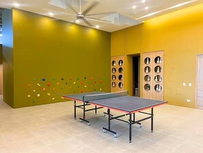 Ein Tischtennis-Tisch in einem Raum mit Kletterwand und Deckenventilator.