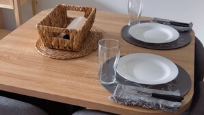 A dining table set with plates, glasses, and a woven basket.