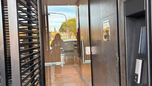An interior corridor with a glass door leading to a lobby area.