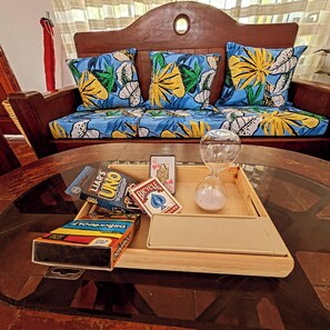 A glass coffee table with board games, a dice, and an hourglass on a wooden tray. - Casa Sol Bacocho (Puerto Escondido)