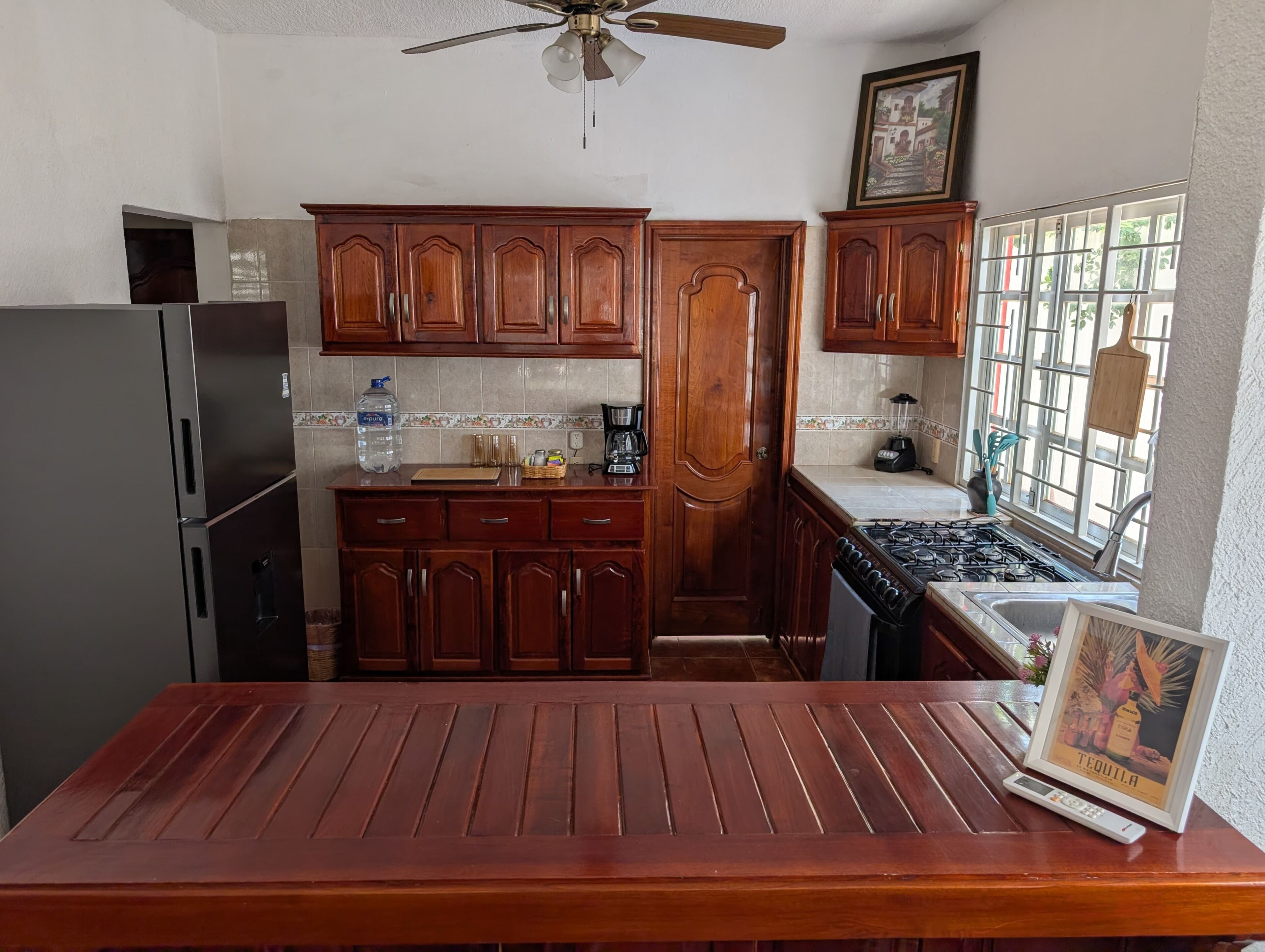 A kitchen with wooden cabinets, a refrigerator, a stove, and a dining table.