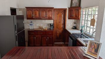 A kitchen with wooden cabinets, a refrigerator, a stove, and a dining table.