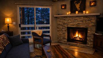 Una sala acogedora con chimenea, un sofá, un sillón y un televisor.