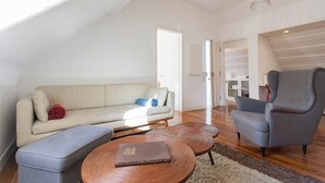 Een moderne woonkamer met een hoge plafond, een bank, een stoel, een bijzettafeltje en een boek.