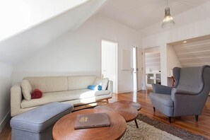 A modern living room with a high ceiling, a sofa, a chair, a coffee table, and a book. - Attic Bairro Alto (Lisbon)