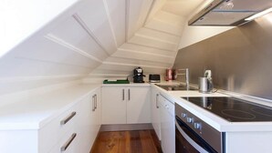 Een kleine keuken met witte kasten, een zwarte kookplaat en een klein aanrecht.