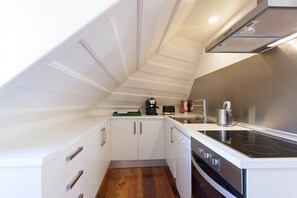 A compact kitchen with white cabinetry, a black stove, and a small countertop. - Attic Bairro Alto (Lisbon)